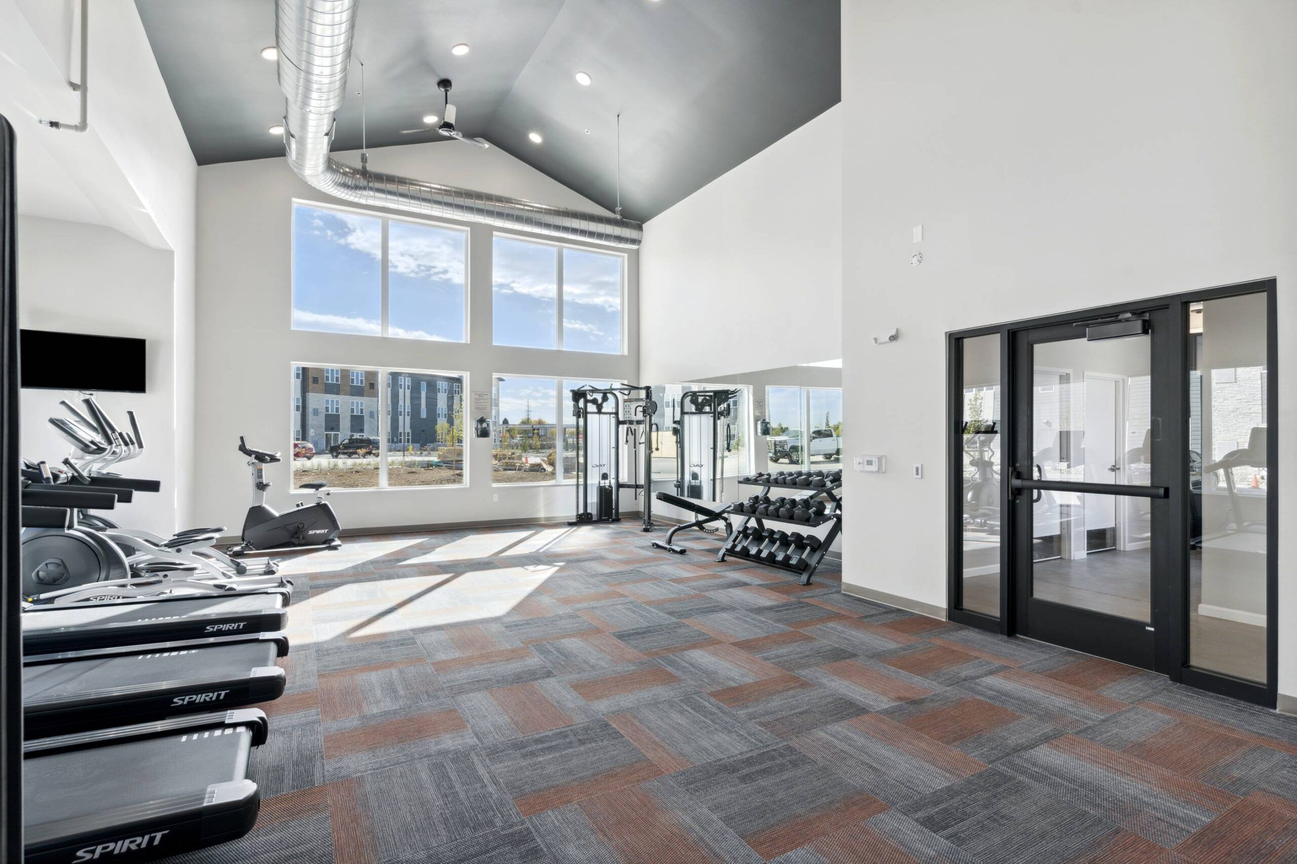 Xcelsior apartment theme lobby with industrial-chic decor, circular chandeliers, communal tables, and a cozy lounge area with plush seating.